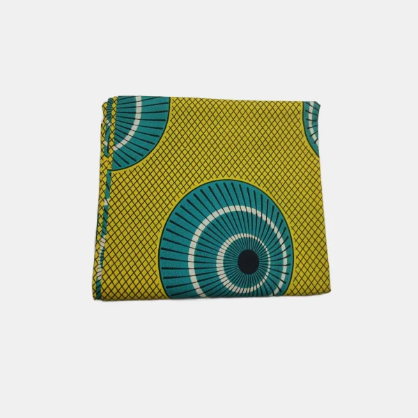 Folded Midas Wheel of Fortune Ankara fabric featuring yellow, teal, and black circular patterns. 100% cotton.